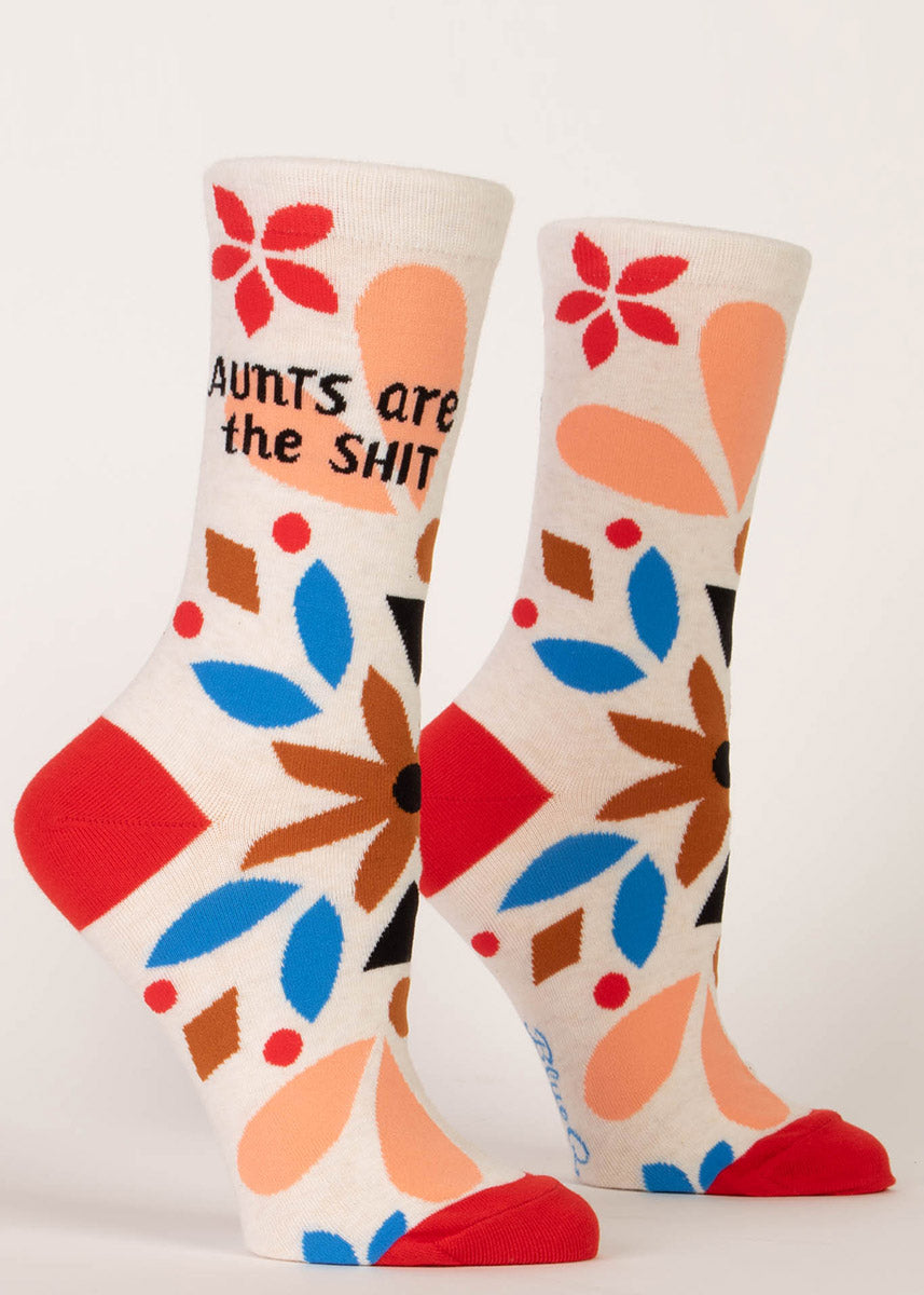 Fun socks that say “Aunts are the shit" with an abstract floral pattern in bold shades of orange, red and blue.