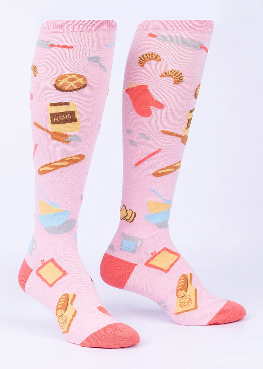 Baker&#39;s knee socks with loaves of bread and a variety of baking tools all on a pink background.