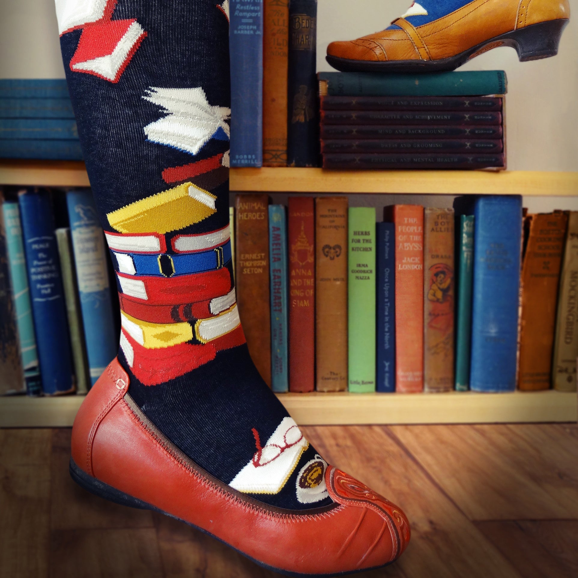 Knee-high book socks for women with stacks of books, flying books and a book being read on a black background
