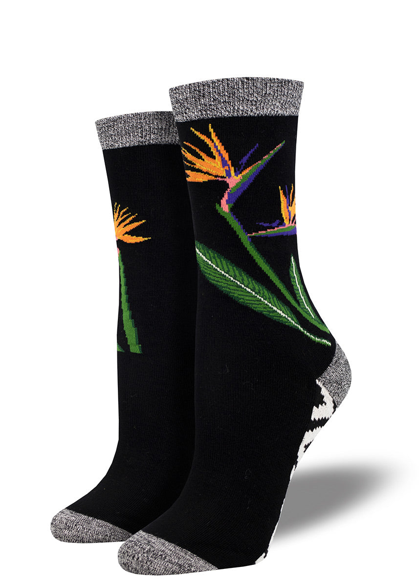 Black bamboo socks with a floral bird of paradise design on the leg, and a wild black and white zigzag pattern on the sole of the foot.