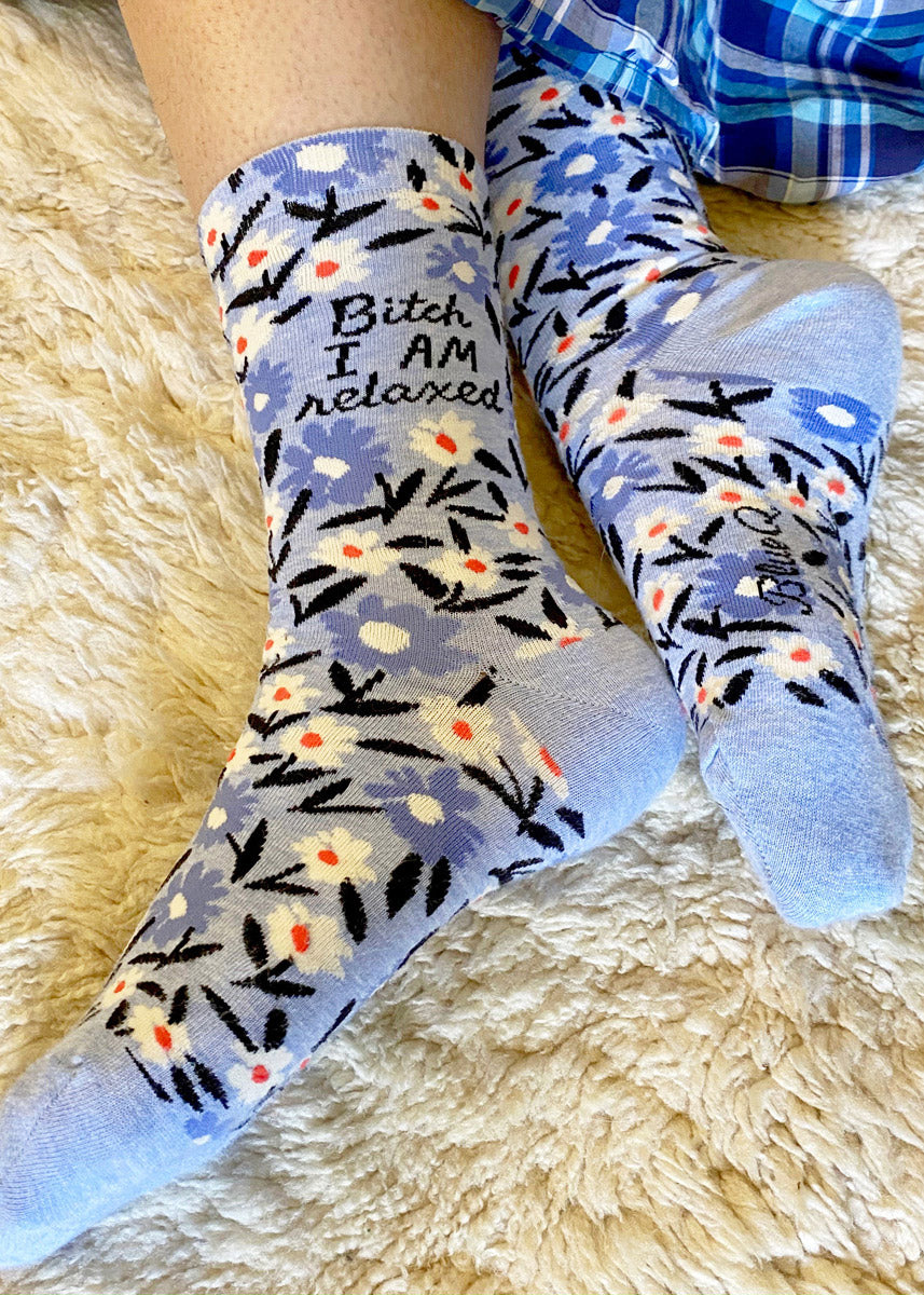 Swear word socks for women say, &quot;Bitch I am relaxed,&quot; surrounded by white and blue flowers.