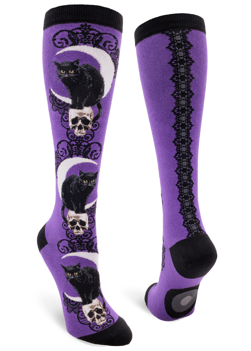 Purple knee socks with a design of black cats, crescent moons and skulls accented with a black lace pattern.