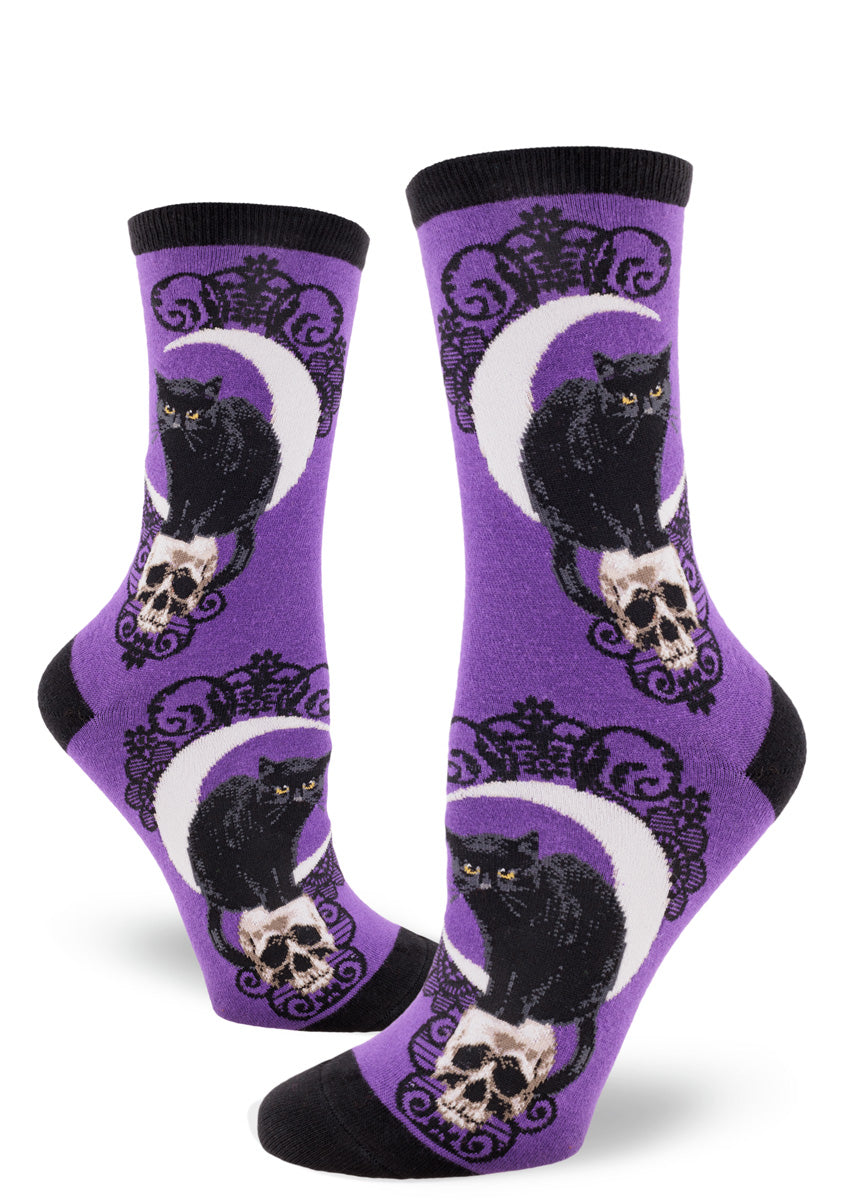 Purple crew socks with a design of black cats, crescent moons and skulls accented with a black lace pattern.