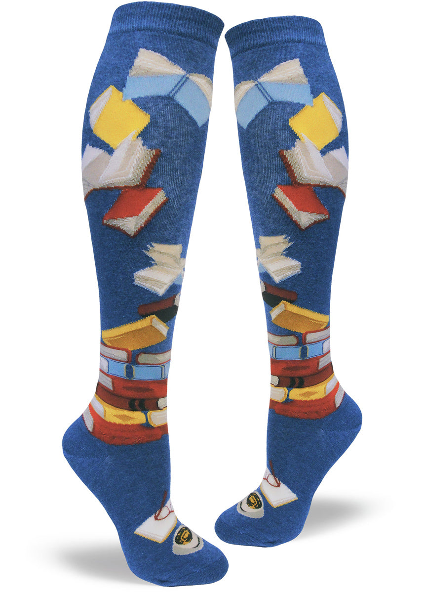 Knee-high book socks for women with stacks of books, flying books and a book being read on a black background