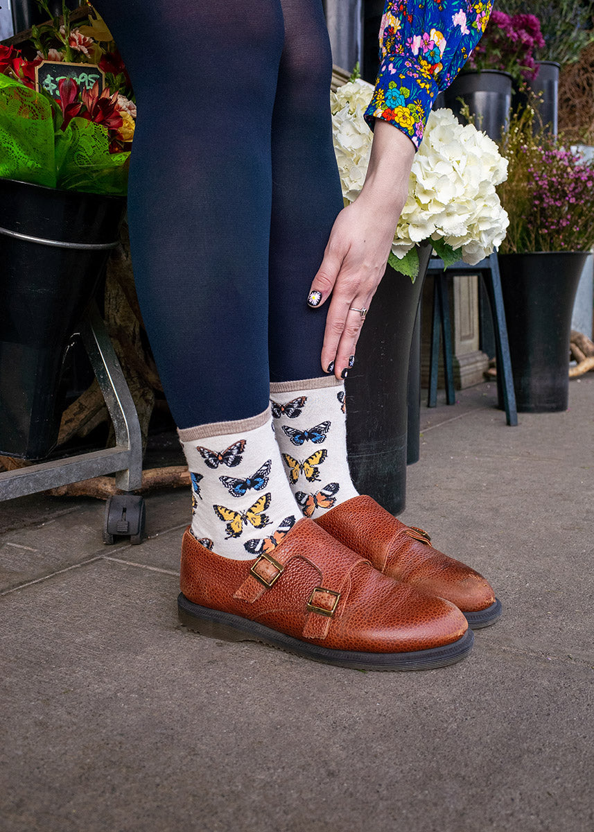 These crew socks for women feature colorful butterflies on a cream background.