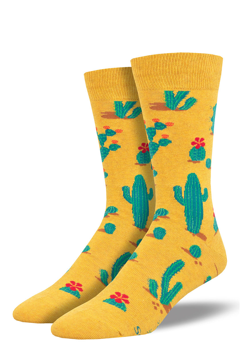 Novelty cactus socks for men have a golden yellow background embellished with green desert cacti and bright red cactus flowers.