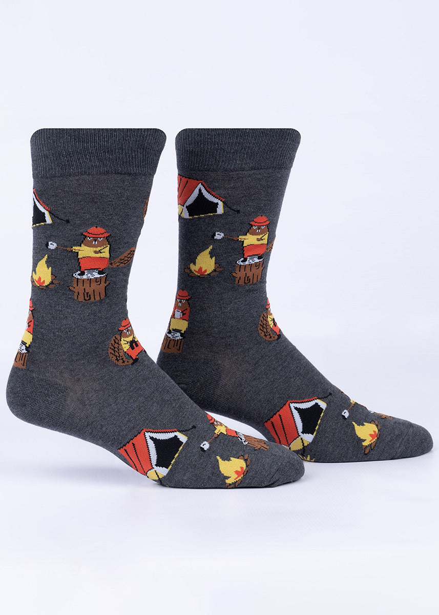Funny beaver socks for men show the buck-toothed animals camping and making s'mores over a campfire with a tent in the background.