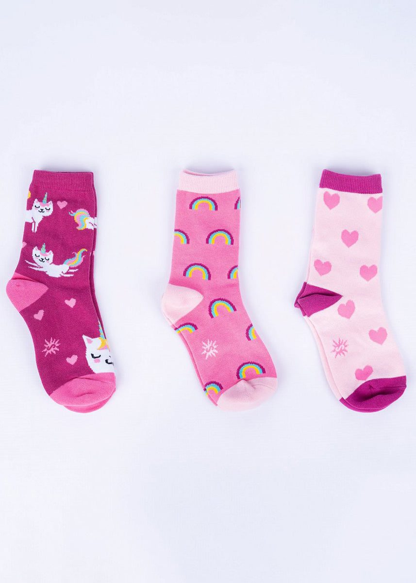 Three pairs of coordinating socks for kids in shades of pink with cat unicorn, rainbow and heart designs.