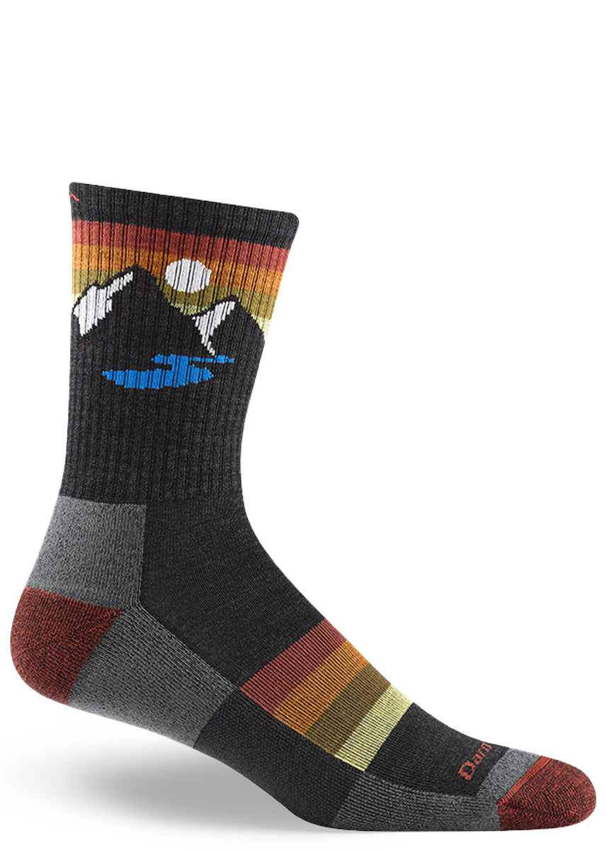 Wool hiking socks for men feature a design of a mountain and a lake under a setting sun and feature footbed cushioning for extra comfort.