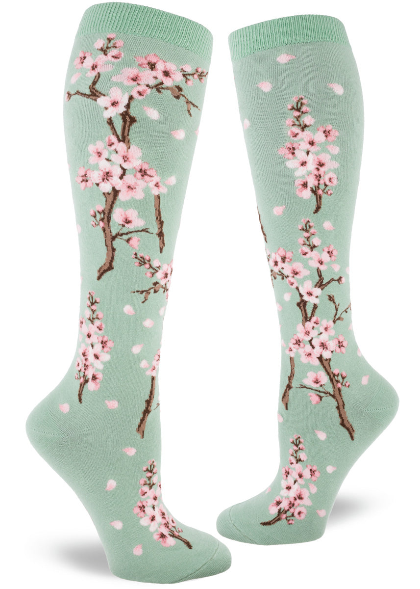 Knee socks for women feature pale pink cherry blossoms on a mint green background.