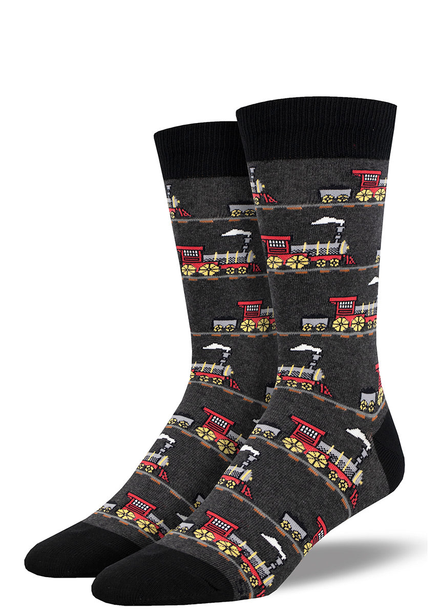 Railroad-themed dress socks for men with a repeating pattern of steam locomotive trains traveling down the track over a charcoal heather background.