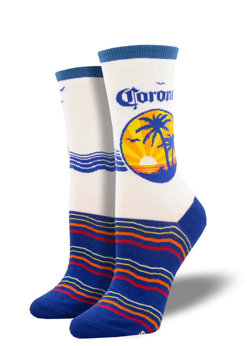 Corona beer socks show a tropical sunset over the beach complete with palm trees on the leg, and colorful striped waves on the foot.