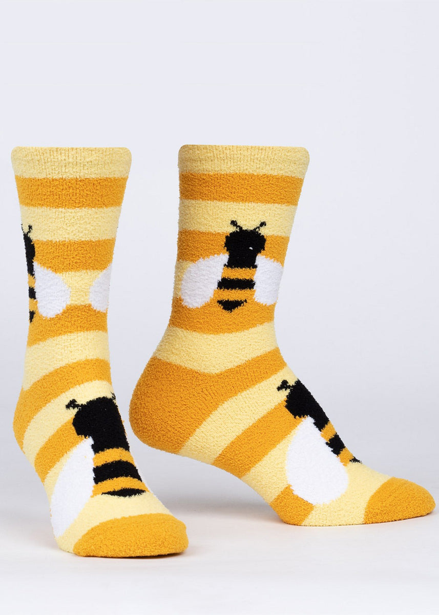 Cozy slipper socks feature a design of honeybees on fuzzy yellow stripes with no-slip grips on the bottom of the foot. 