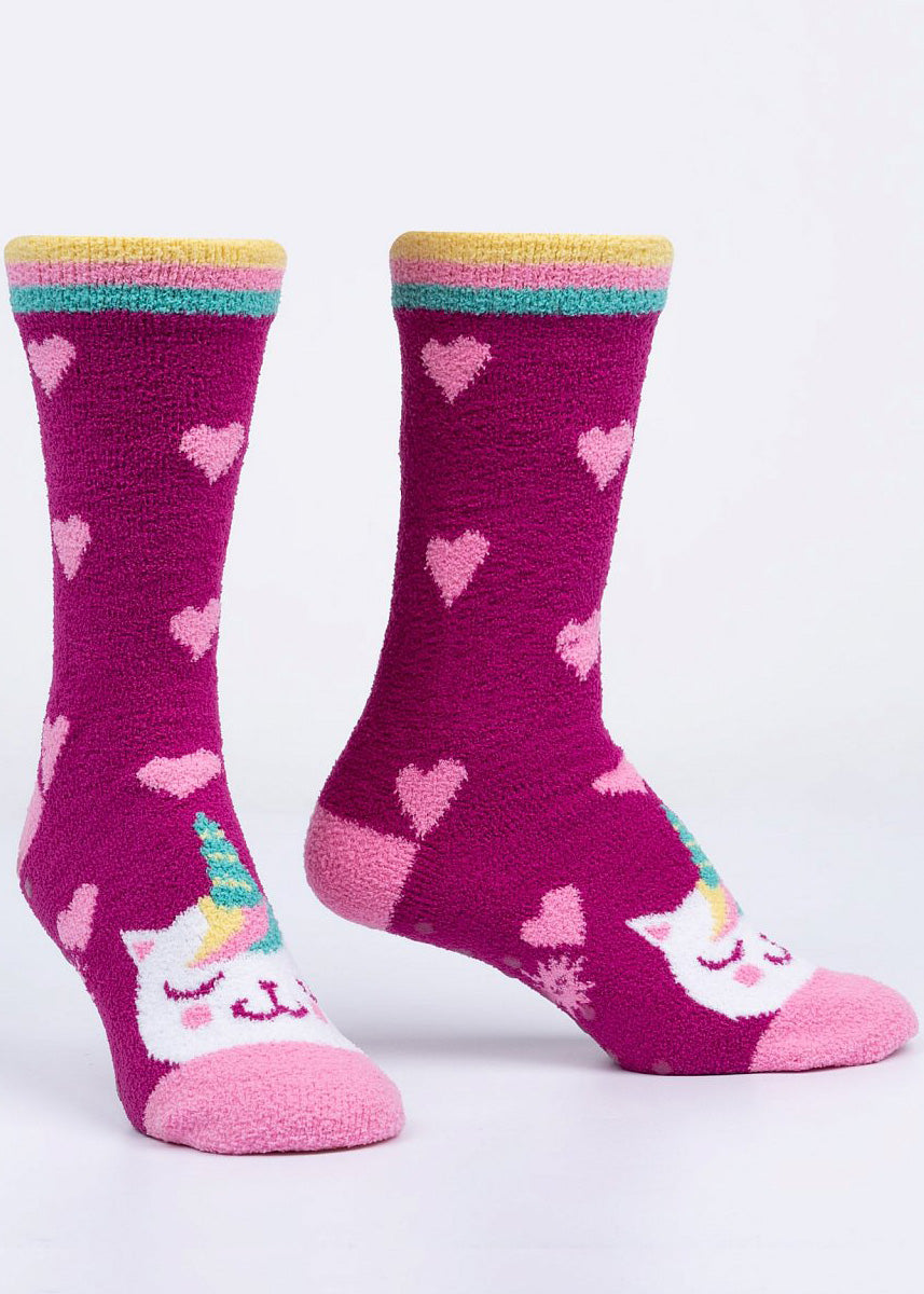 Fuzzy slipper socks feature smiling cat-unicorns with light pink hearts on a dark pink background.