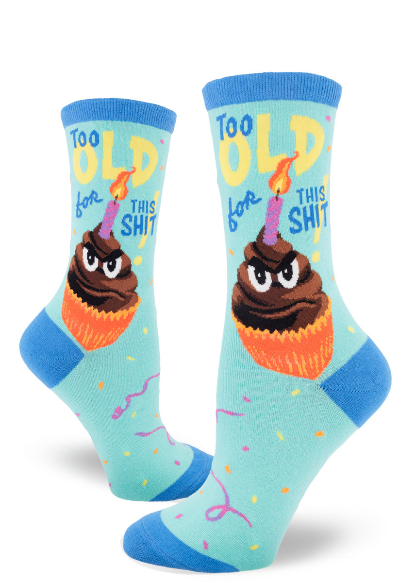 Birthday crew socks for women feature a grumpy anthropomorphized cupcake with a candle stuck in his chocolate frosting and the words “Too Old for This Shit!” 