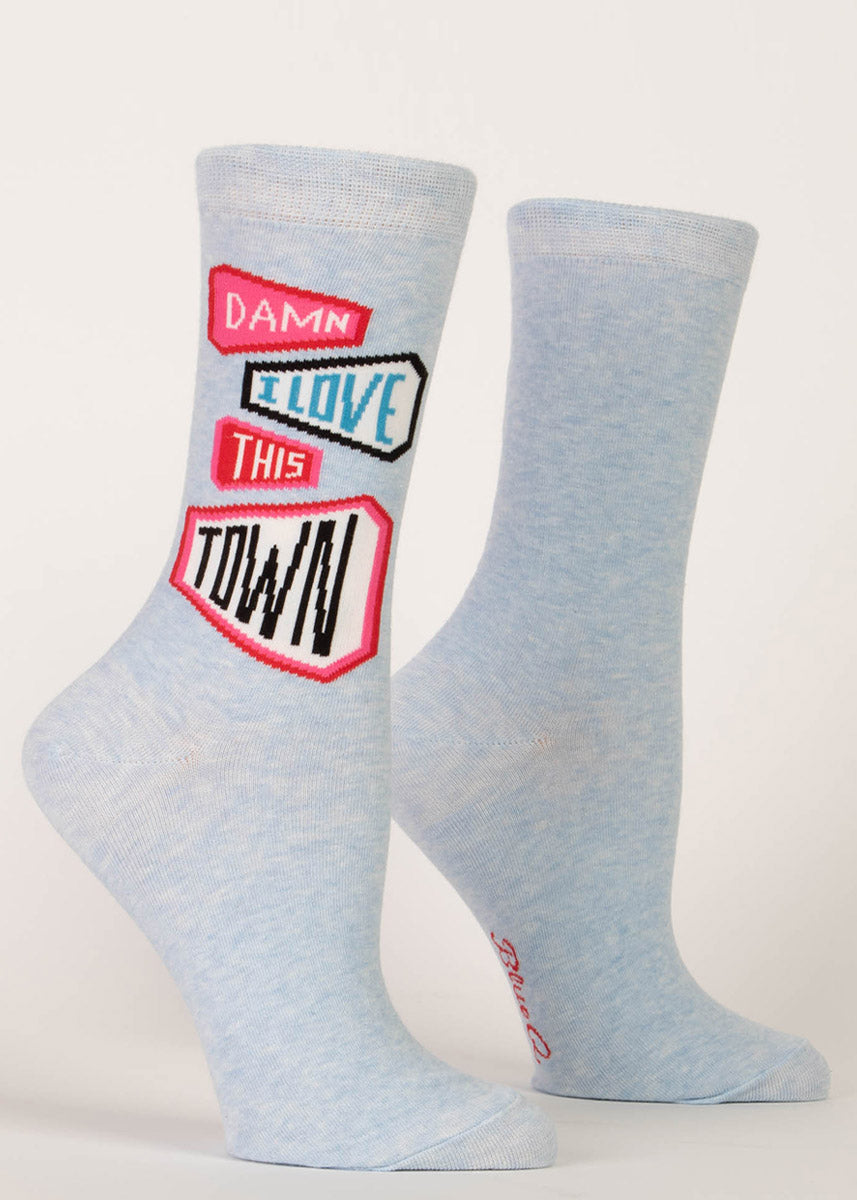 Light blue women&#39;s crew socks with a pattern of pink and black pennants that say “Damn I love this town.”