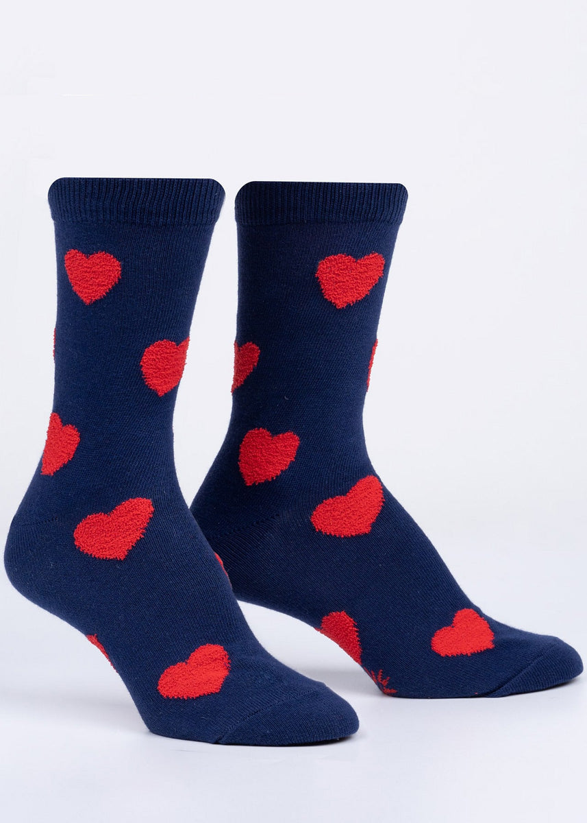 Fuzzy socks for women feature red hearts on a navy blue background.