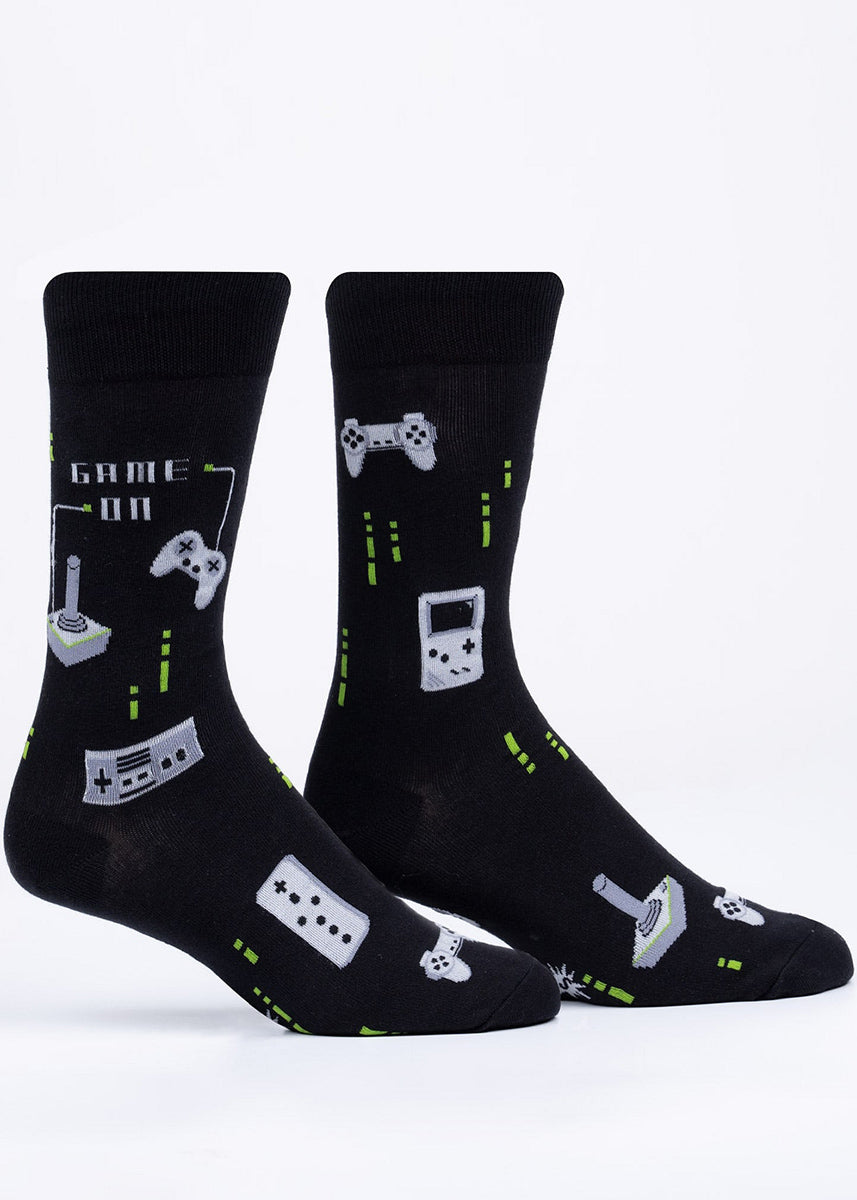 Glow-in-the-dark crew socks for men feature retro game controllers with the words "Game on."
