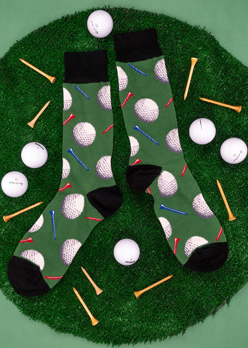 Golf socks for men with golf balls and golf tees, with a green background.