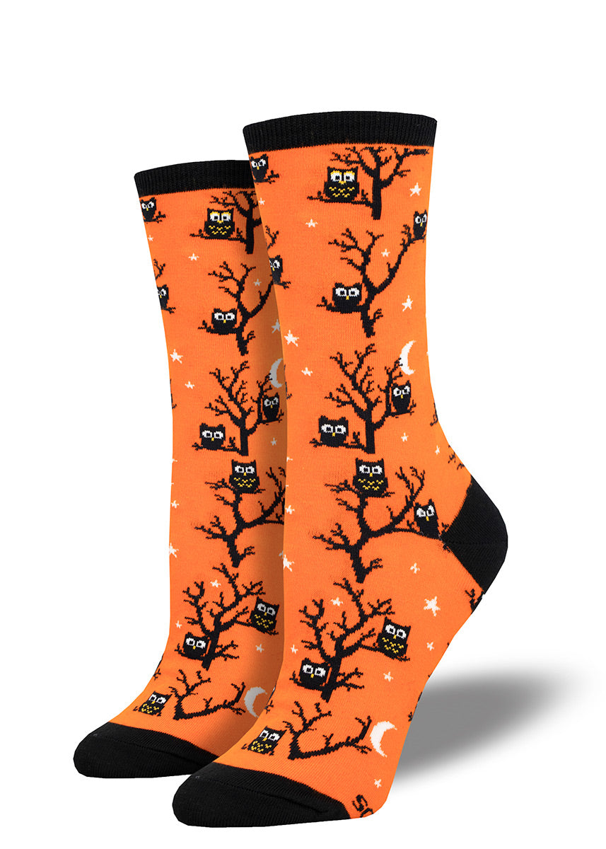 Halloween crew socks feature black silhouettes of owls and trees against a bright orange background dotted with white stars and moons.