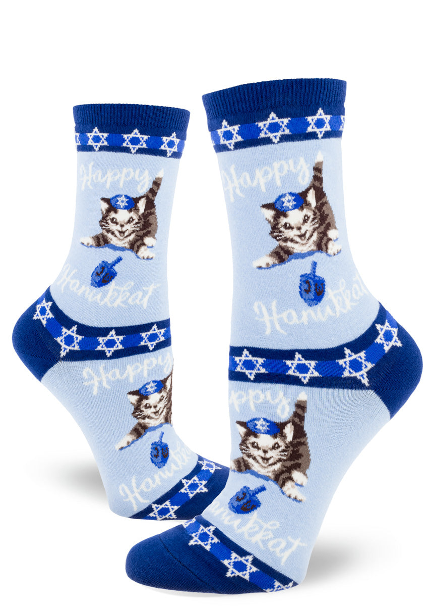 Cute Hanukkah socks for women feature adorable cats playing with blue dreidels and the words, "Happy Hanukkat!" 