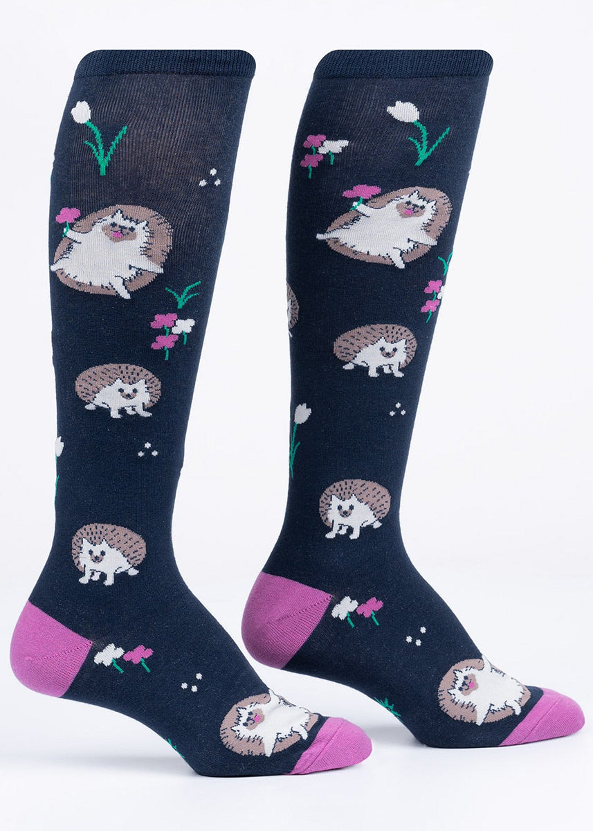 Navy knee-high socks with a pattern of hedgehogs and magenta flowers.