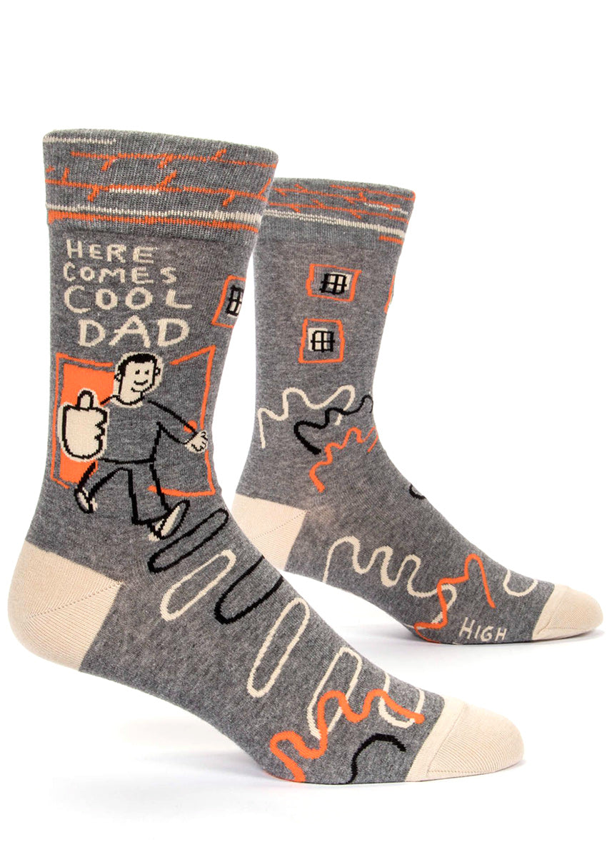 Funny men's socks that say "Here comes cool dad" with a dad giving a thumbs-up on gray socks