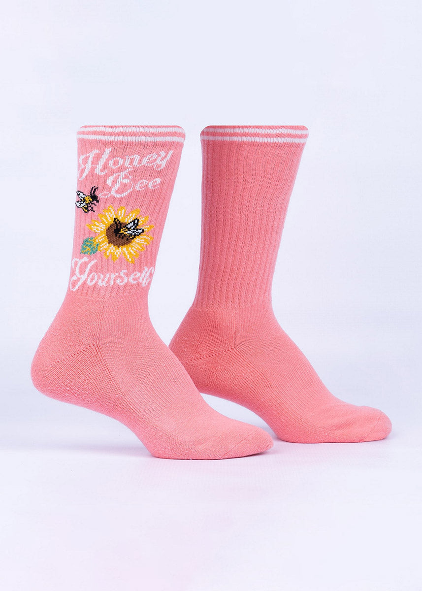 Ribbed pink crew socks with bees flying around a sunflower and the words “Honey Bee Yourself" on the leg. 