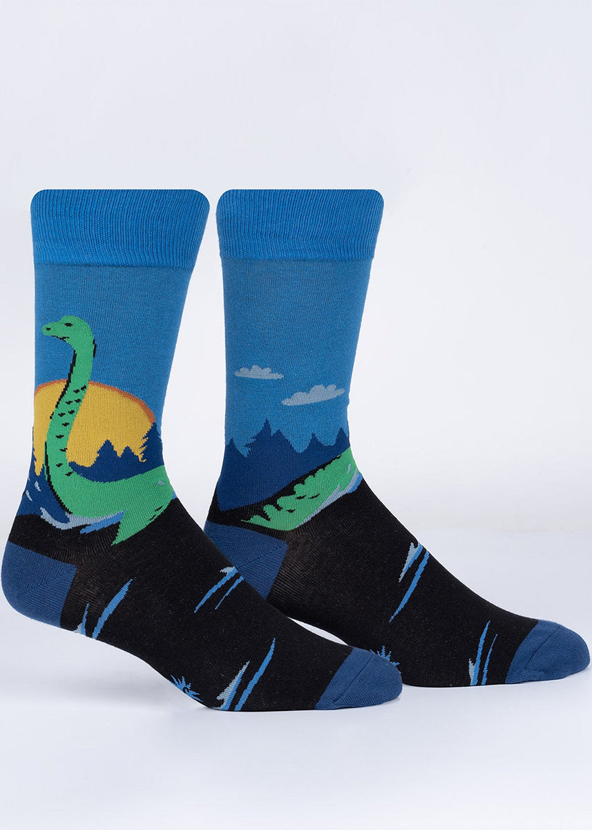 Cool cryptid socks show a green Loch Ness Monster raising her long neck in front of a rising sun and a blue sky.