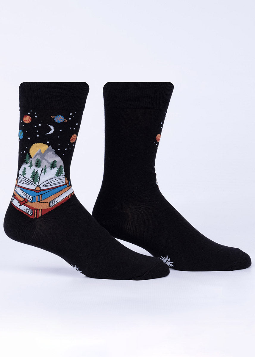 Black dress socks for men with a stack of books, one opened up to show a mountain, a forest and a sky full of planets and stars, all emanating from its pages