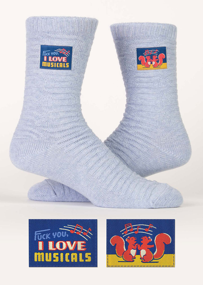 Light blue heather organic cotton socks knit with a textural stripe pattern and embellished with small decorative stitched-on tags that proudly proclaim “Fuck you, I love musicals.”