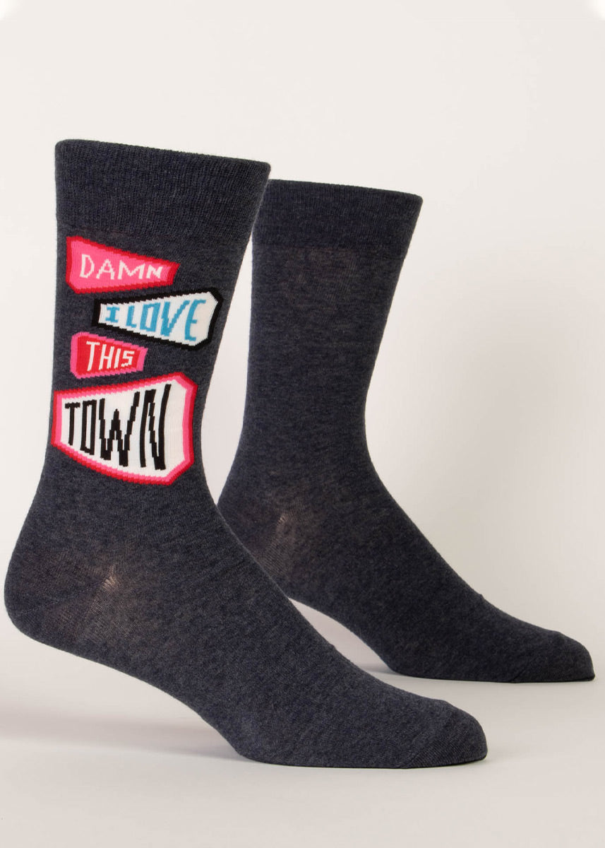 Charcoal men&#39;s crew socks with a pattern of pink and black pennants that say “Damn I love this town.”