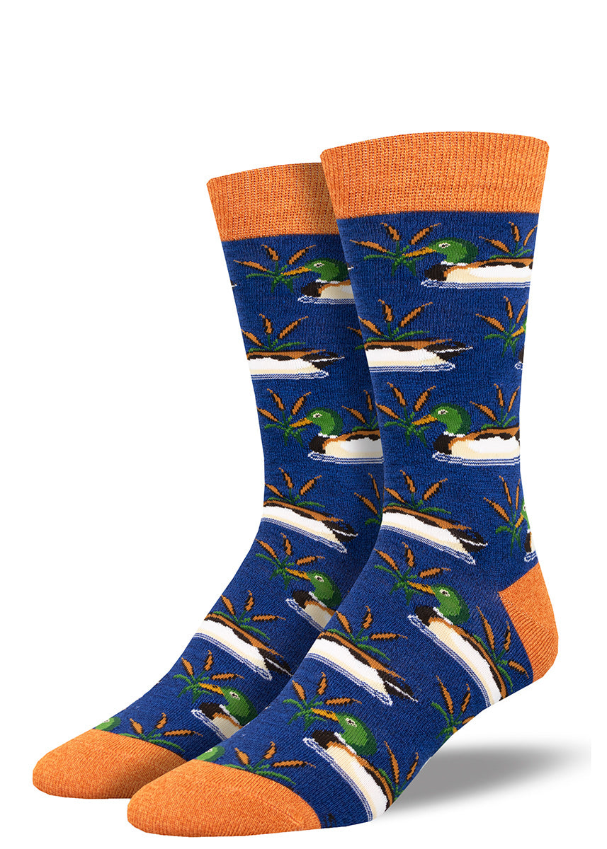 Navy dress socks for men with orange accents at the heel, toe and cuff are covered in a pattern of male mallard ducks swimming between cattails.