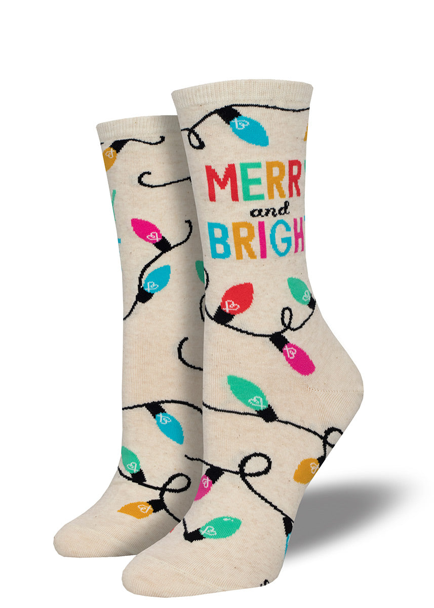 Novelty crew socks for women feature a colorful string of Christmas lights and the words “Merry and Bright” against a heather ivory background.