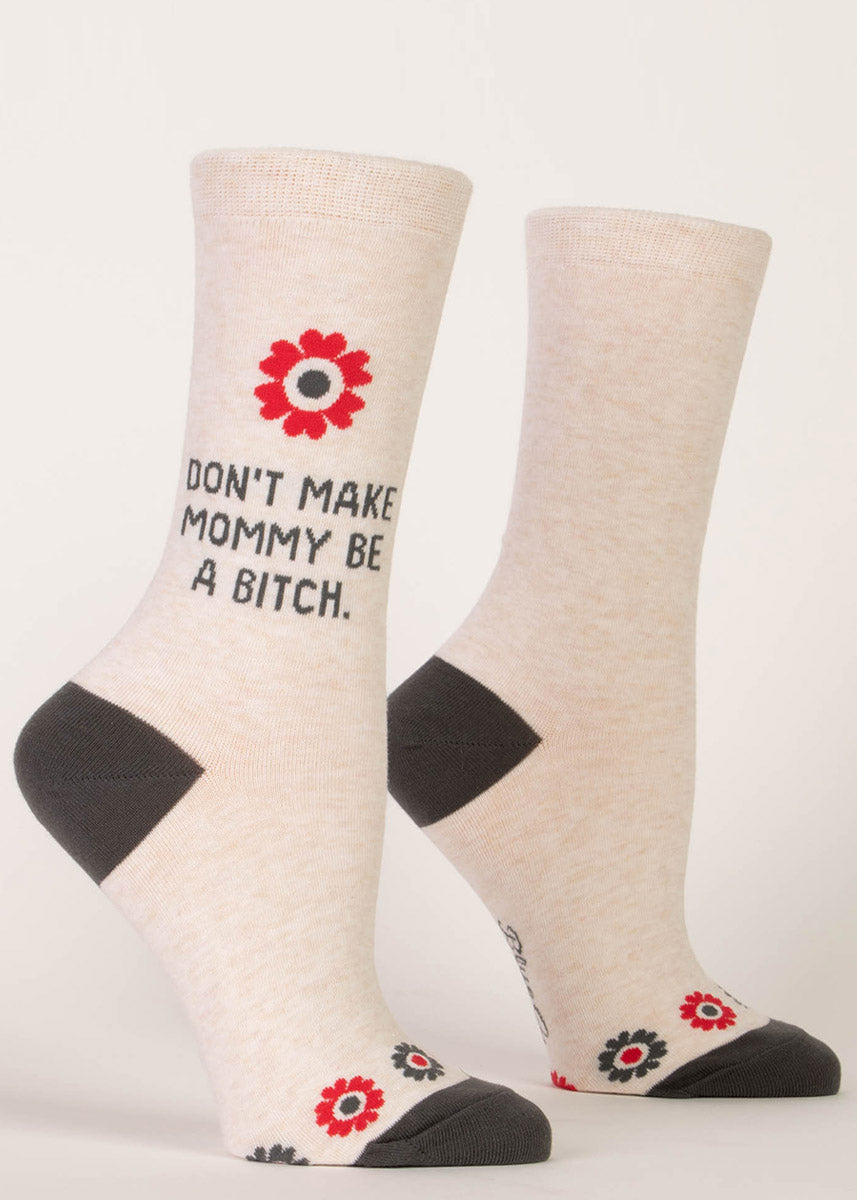 Funny socks that say “Don't make mommy be a bitch" on a cream background with a simple daisy design.