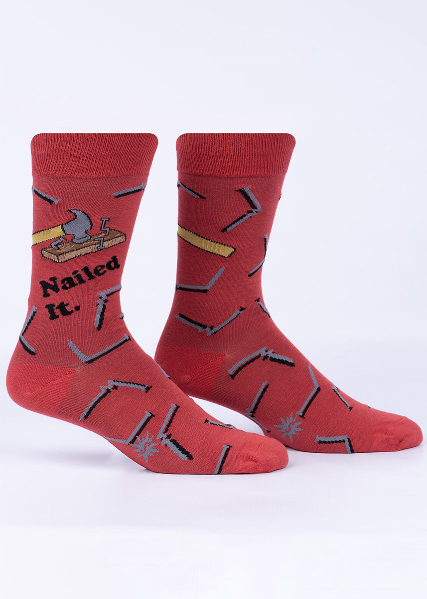 Funny men's socks with a design of hammers and bent nails, along with the words “Nailed It.”