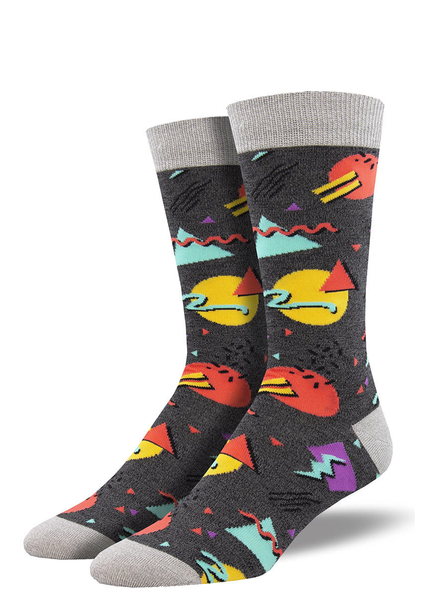 Fun novelty socks for men with a Memphis design in bright colors, funky shapes, crazy confetti and sketchy squiggles over a charcoal background.