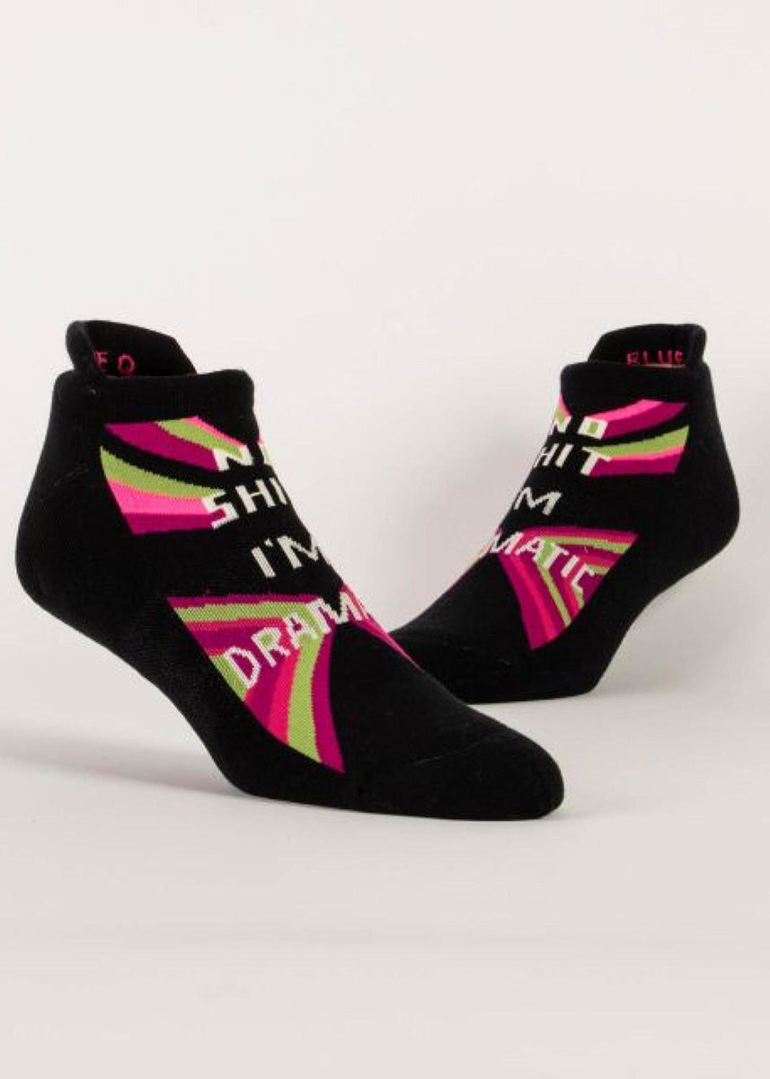 Black athletic ankle socks that say “No Shit I&#39;m Dramatic” on a pattern of vivid pink and green geometric designs.