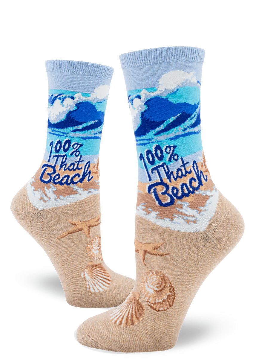 Funny socks for women show a beach scene with crystal blue waves and golden sand and the words, "100% That Beach."