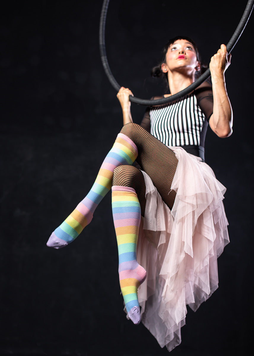 Knee high socks for women have pastel rainbow stripes in pale pink, orange, yellow, mint, blue, and purple.