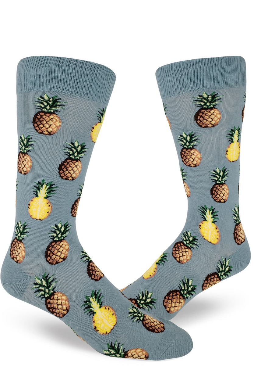 Tropical pineapple socks for men with pineapples sliced in half or whole on a slate blue background