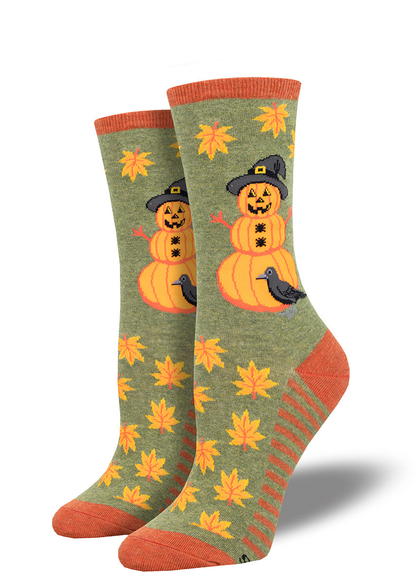 Halloween crew socks with a pumpkin man, like a snowman but made of pumpkins, and a smattering of fall leaves on a green background.
