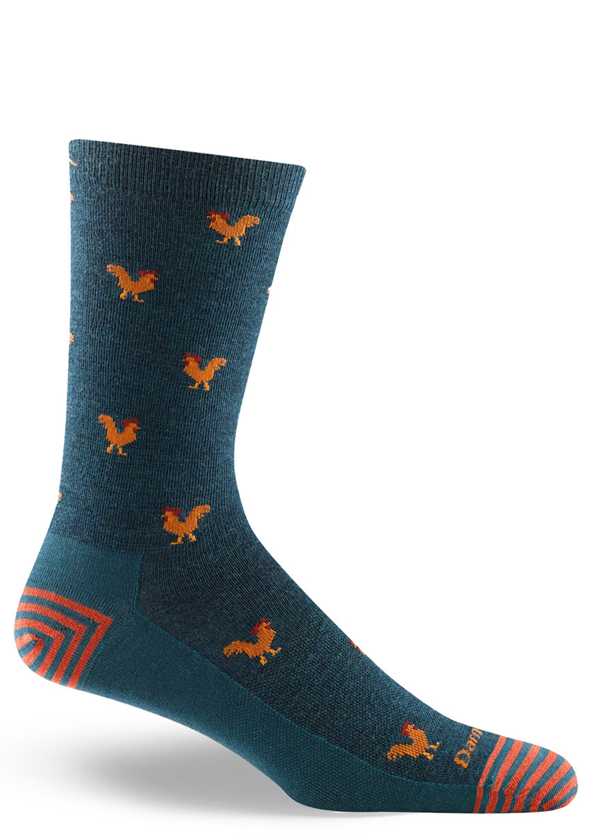 Wool crew socks for men feature a pattern of tiny roosters on a dark teal background.
