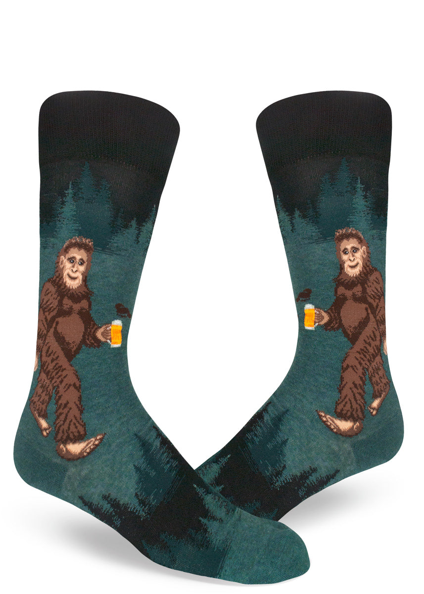 Sasquatch beer socks for men with a bigfoot drinking beer in the woods with trees behind him