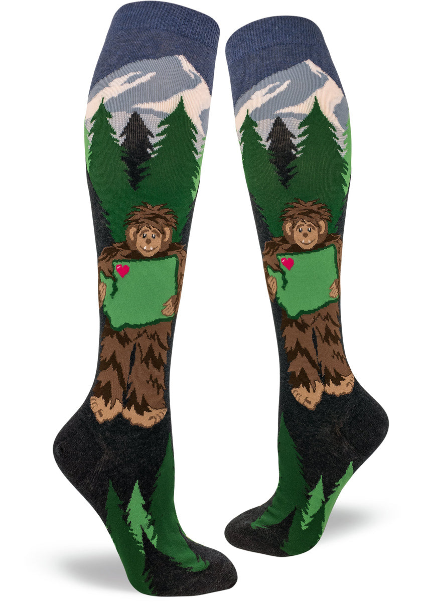 On Sasquatch Loves Washington knee-high socks, Bigfoot holds Washington state with trees and mountains