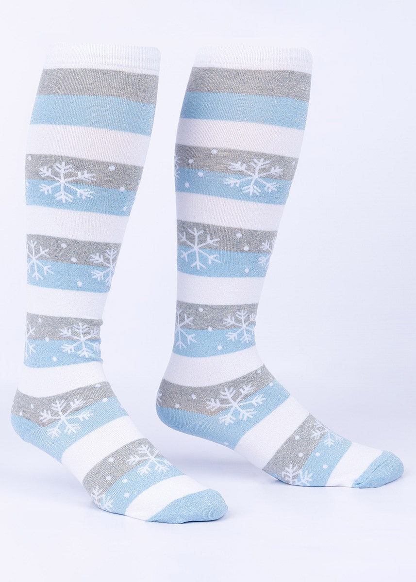 Knee-high socks embellished with a snowflake design and shimmering silver thread over soft white, blue and gray stripes.