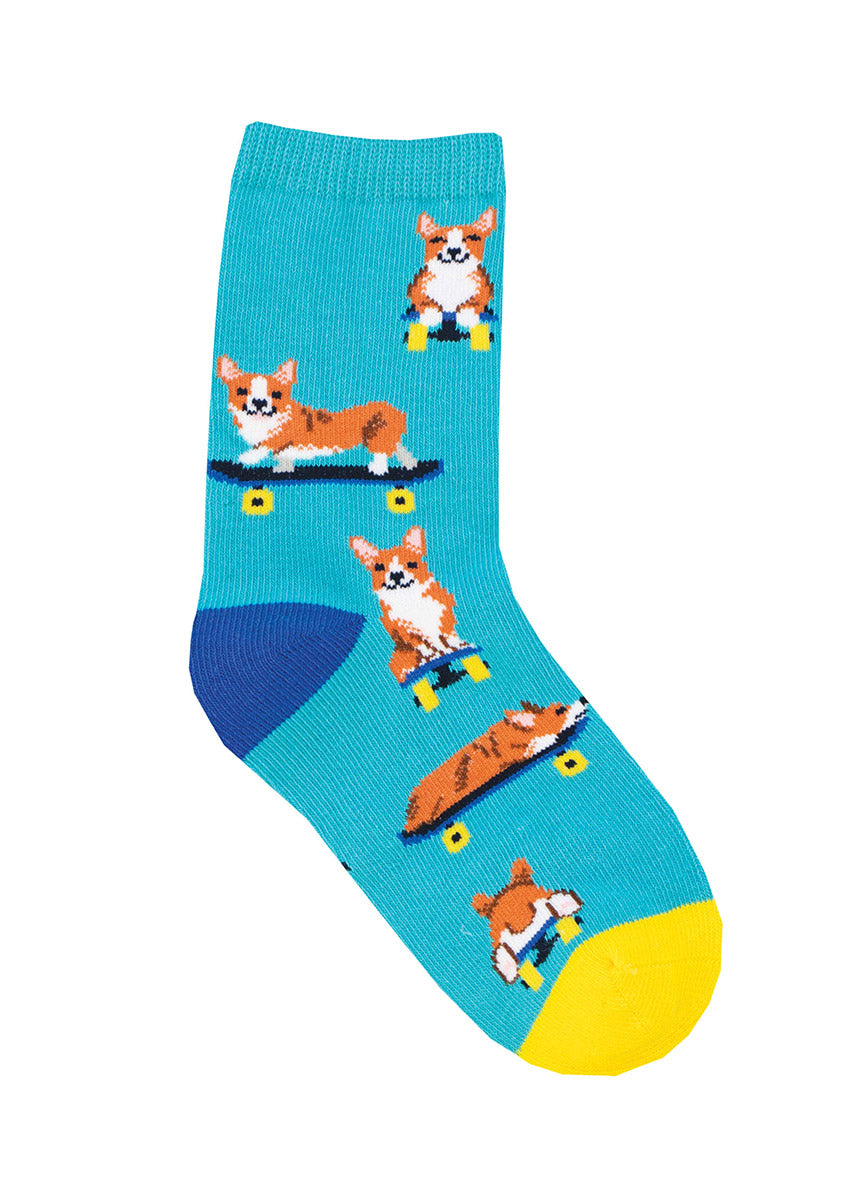 Blue crew socks for kids with an allover pattern depicting a corgi dog riding a skateboard.