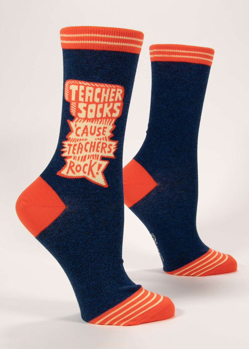 Heather navy women's crew socks with vivid orange accents and retro schoolhouse-styled lettering that says "Teacher Socks 'Cause Teachers Rock!”