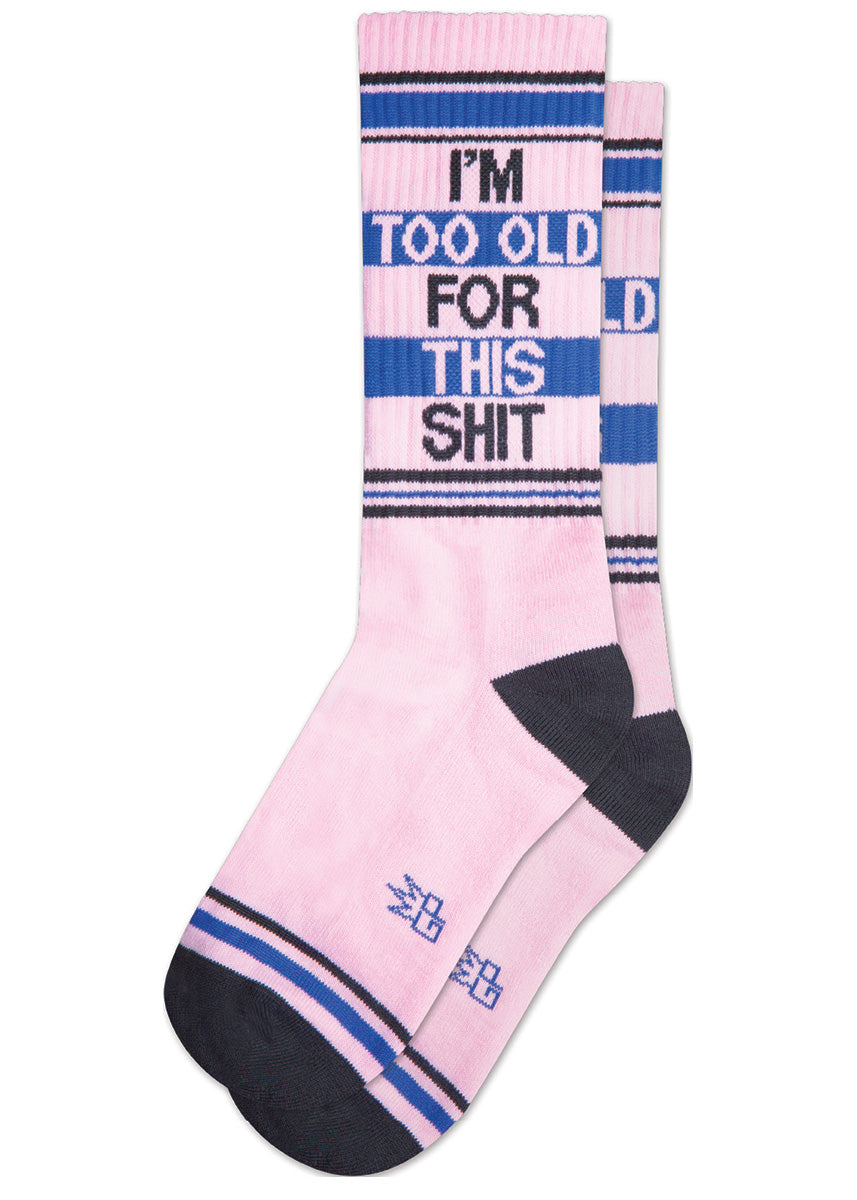 Retro athletic-style crew socks say “I&#39;m Too Old For This Shit” on a pink background with stripes in blue and black.