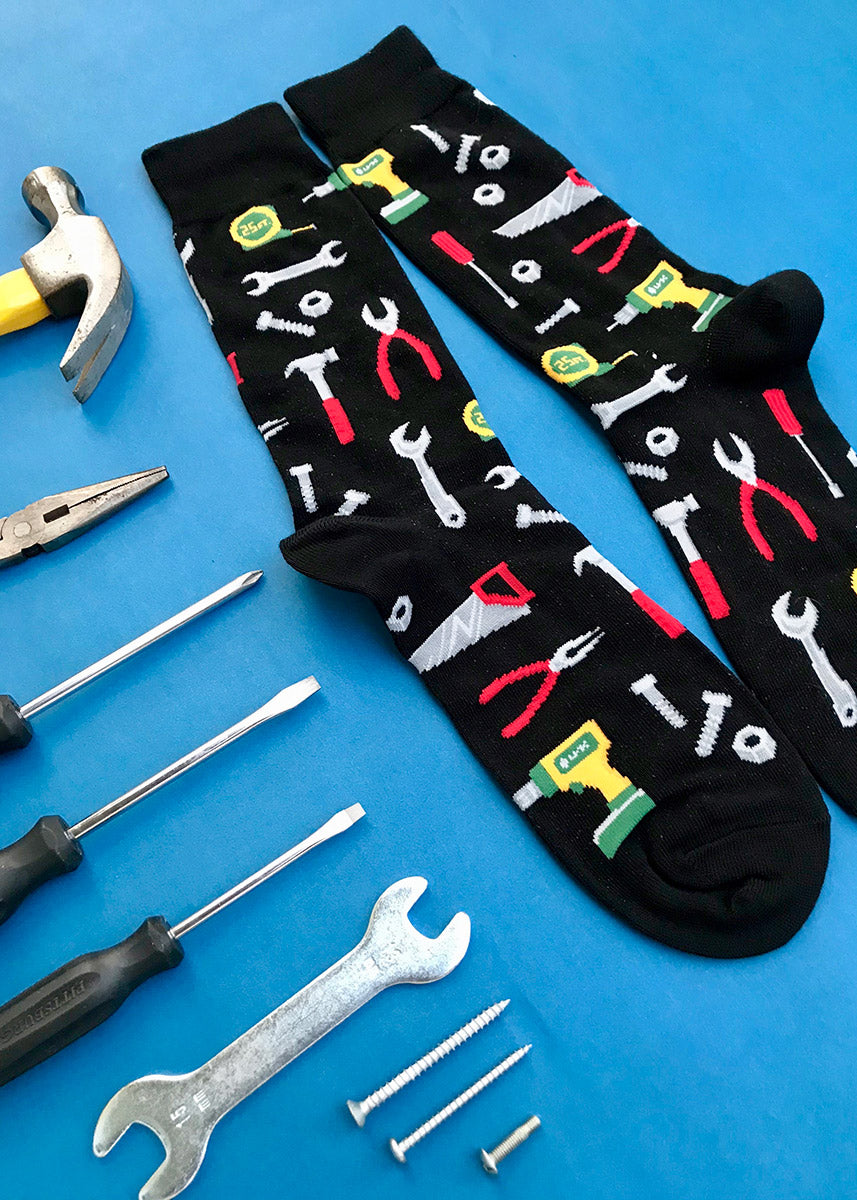 Crew socks for men feature tools like drills, wrenches, hammers, and more on a black background!